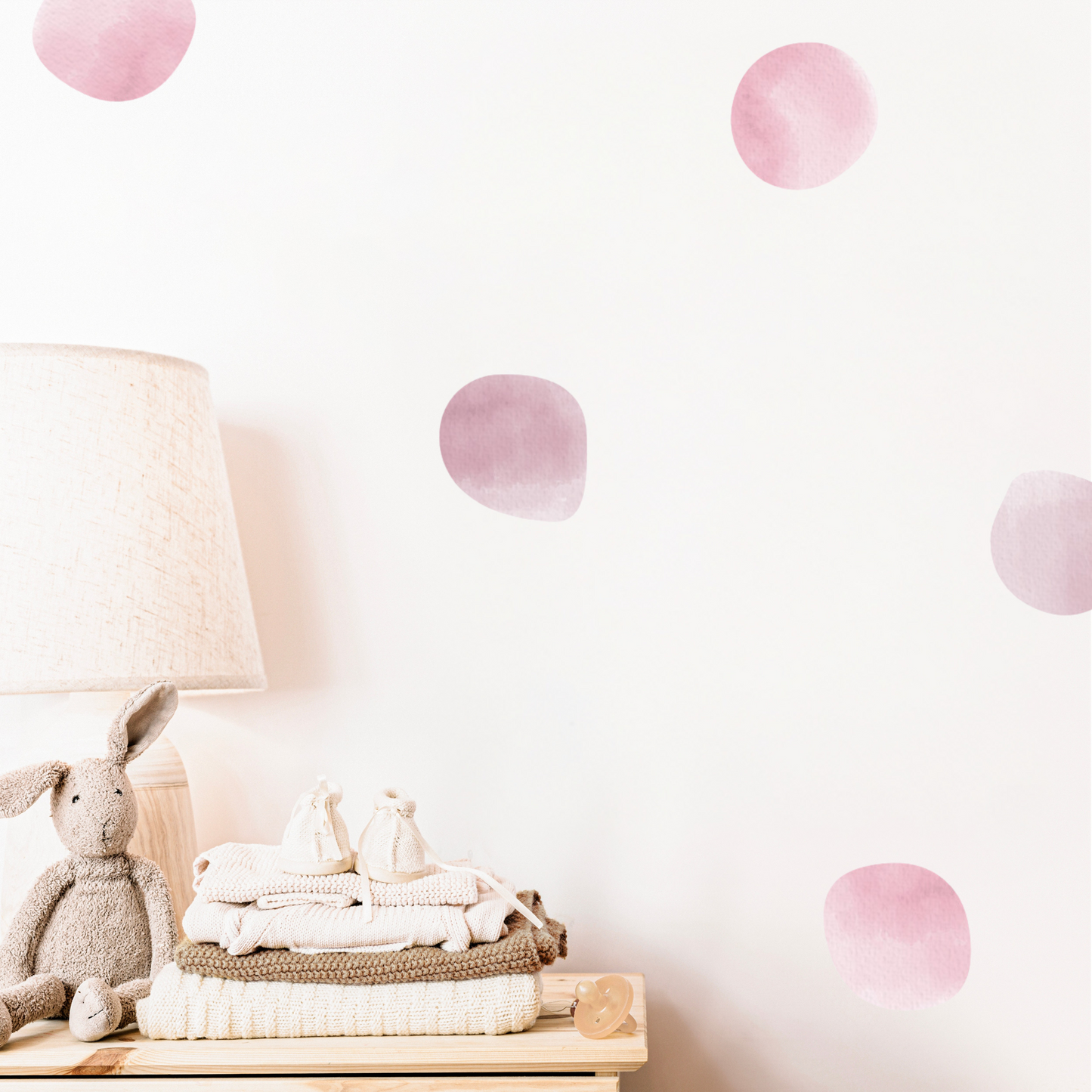 Children's room with pink polka dot wall decals, a lamp, and stuffed animals.