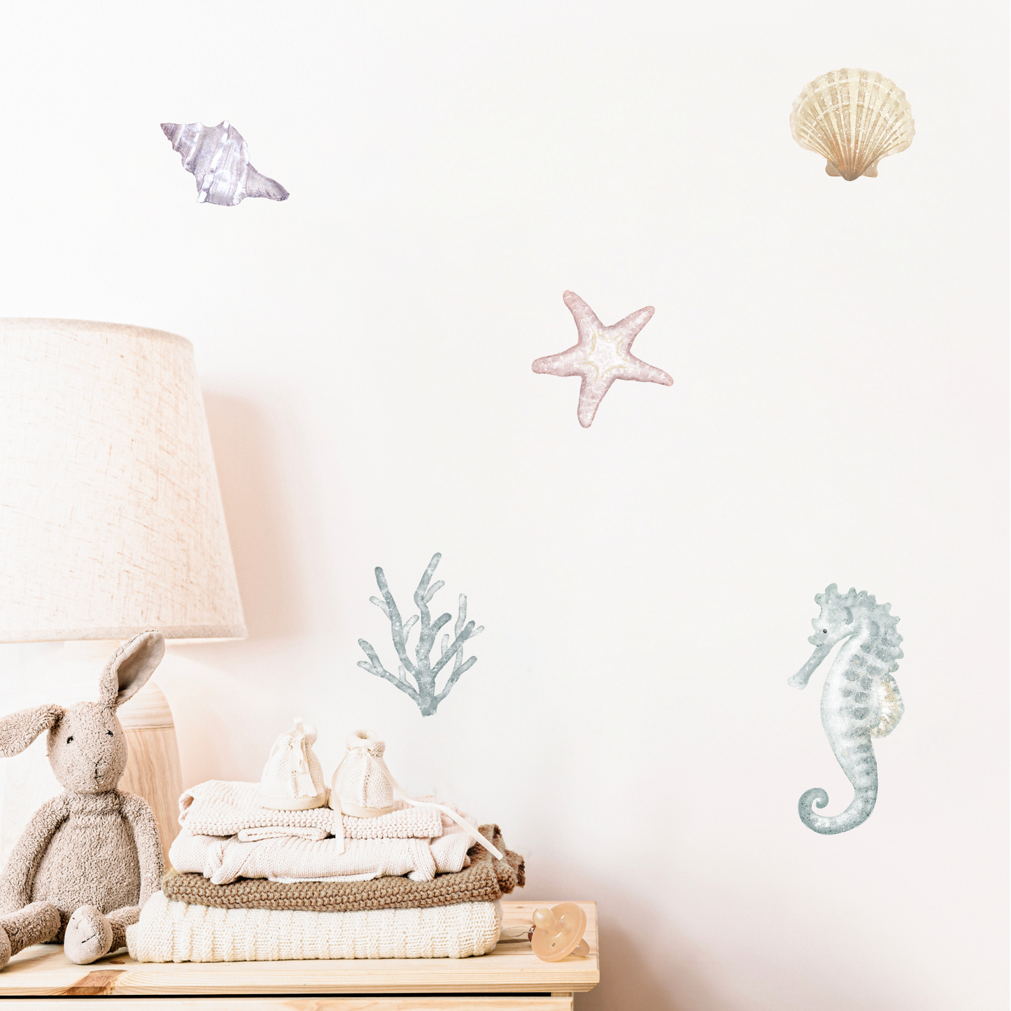 Watercolour wall stickers of seashells, starfish, coral and seahorses on a white wall above a wooden shelf with toys. Non-toxic, eco-friendly, reusable wall stickers. Australian made.
