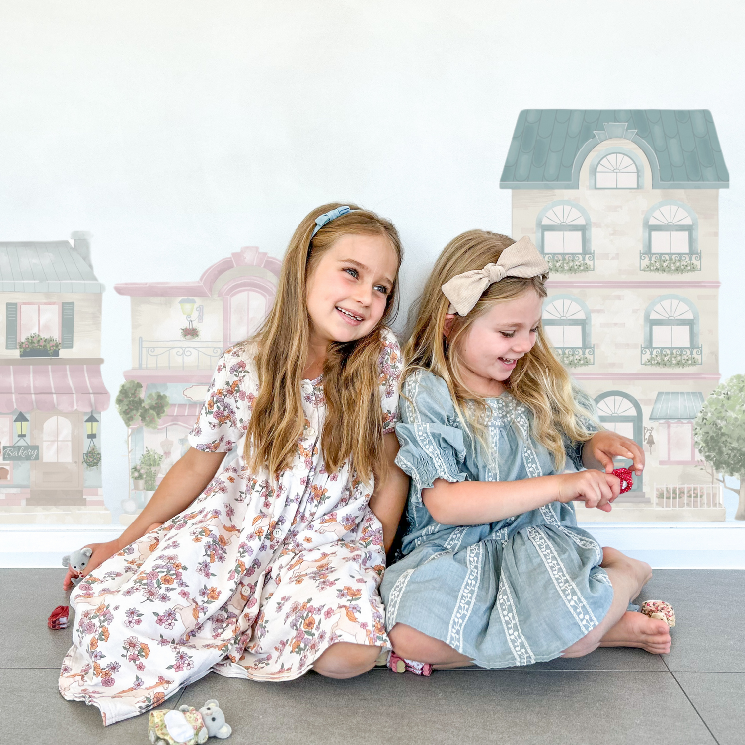 Little Village wall decals on a child's bedroom wall.  The town features a house, café, florist, bakery, dress shop as well as trees, bushes, a bike and ice-cream cart.  Non-toxic, eco-friendly, reusable wall stickers. Australian made.
